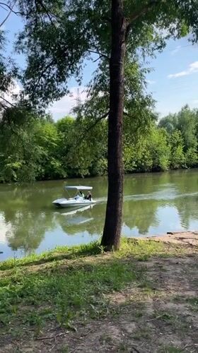 Small canopied boat glides through a lush green Russian waterway