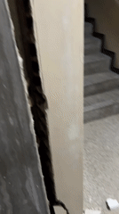 Cracked walls and exposed brickwork inside a Caracas building