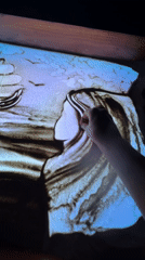 Sand art taking shape on a glowing light table in Bali