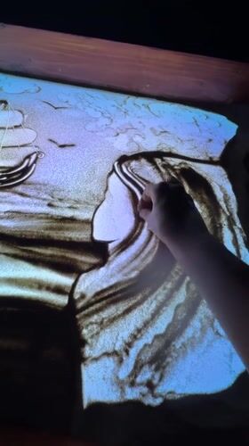 Sand art taking shape on a glowing light table in Bali