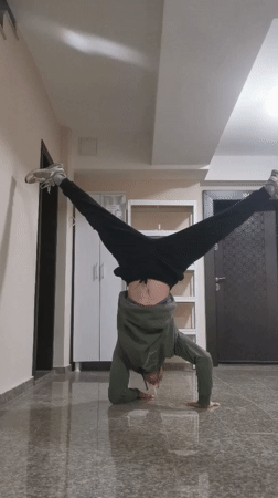 Person performs headstands and kicks in Bulgarian building hallway