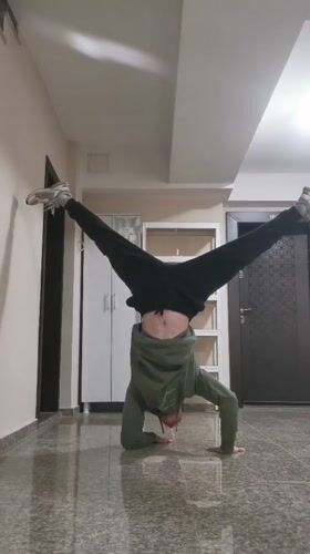 Person performs headstands and kicks in Bulgarian building hallway