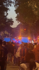 Sports fans gather near emergency vehicles at dusk