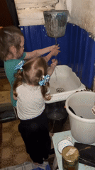 Two girls wash hands in rustic setting