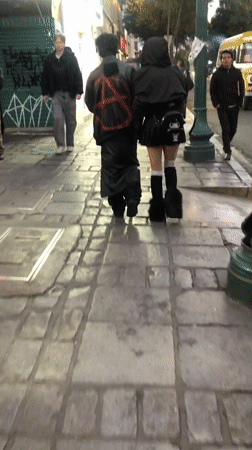 Two pedestrians walk cobblestone sidewalk in La Paz