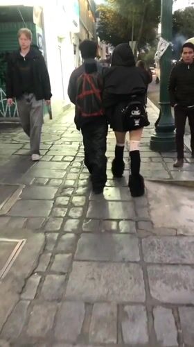 Two pedestrians walk cobblestone sidewalk in La Paz