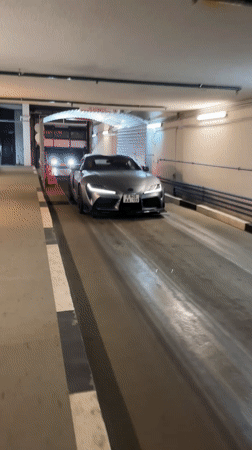 Gray Toyota Supra drives through illuminated car wash tunnel