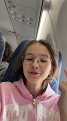 Teen in pink hoodie filmed talking excitedly on airplane