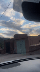 Driver records Moroccan castle buildings during evening journey near Asni