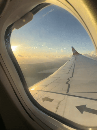 Passenger films sunrise sky view from airplane window near Kuta