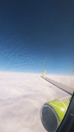Passenger films cloudy skies from airplane window over Russia