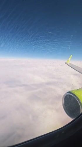 Passenger films cloudy skies from airplane window over Russia