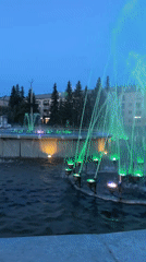 Colorful fountain light show captivates urban square at dusk
