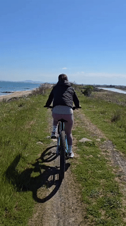 Woman cycles rural dirt path near beach in Pomorie