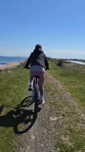 Woman cycles rural dirt path near beach in Pomorie
