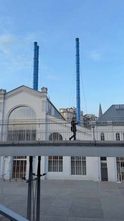 Man crosses pedestrian bridge between white buildings in Moscow