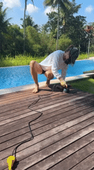 Worker sands wooden pool deck in Ubud, Indonesia