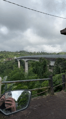 Motorcycle crosses bridge over green valley in Petang, Indonesia
