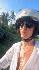 Woman on moped smiles at observer in Kediri