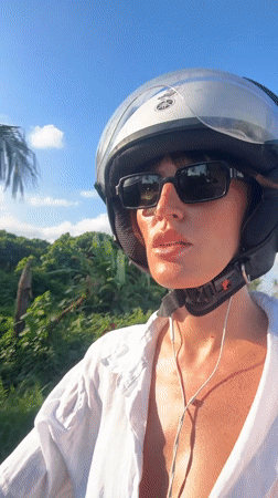 Woman on moped smiles at observer in Kediri