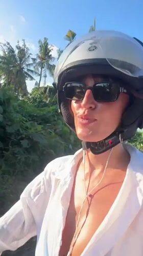 Woman on moped smiles at observer in Kediri