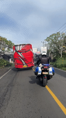 Tourism bus followed by military police motorcycle in Kuta Selatan