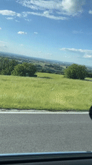 Car travels sunny hillside road on Thursday afternoon