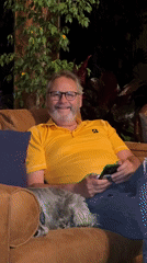 Man with dog relaxes on couch checking phone