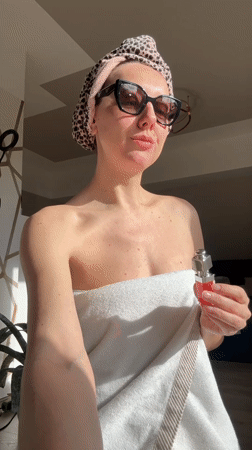 Woman in towel applies makeup indoors in Carnikava