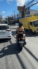 Two passengers on scooter travel alongside white car in Ungasan