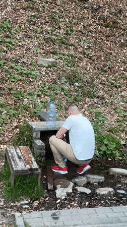 Man fills bottle at spring in Wisła, Poland