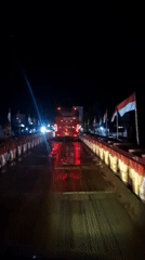 Nighttime bridge crossing with illuminated red bus captured in Indonesia