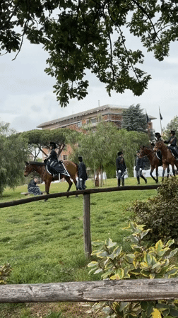 Uniformed horsemen parade across Rome field in ceremonial procession