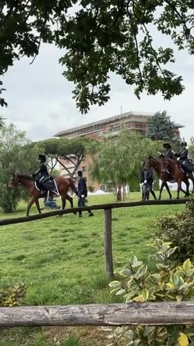 Uniformed horsemen parade across Rome field in ceremonial procession