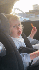 Toddler in car seat holds cracker in Tel Aviv