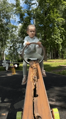 Child plays at lakeside park with broken equipment, submerged boats
