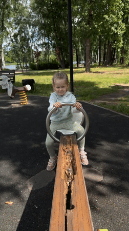 Child plays at lakeside park with broken equipment, submerged boats