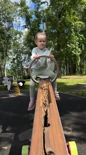 Child plays at lakeside park with broken equipment, submerged boats