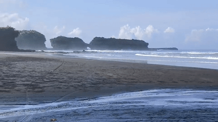 Dark spheres scattered across beach sand in Selemadeg, Indonesia