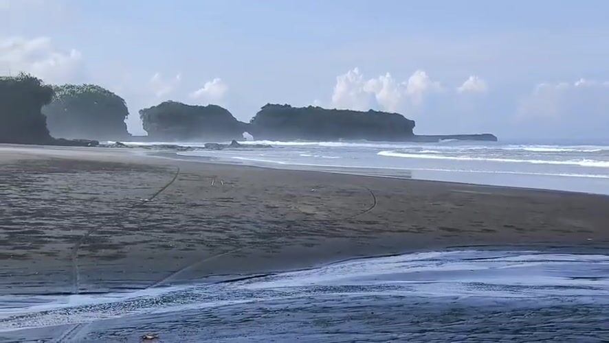 Dark spheres scattered across beach sand in Selemadeg, Indonesia