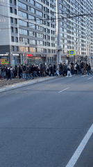 Pedestrians cross busy urban intersection during afternoon rush