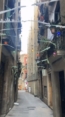 Colorful lights and balcony plants line a Barcelona alleyway