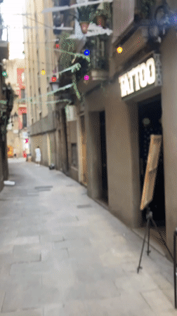 Colorful lights and balcony plants line a Barcelona alleyway