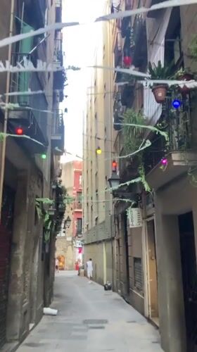 Colorful lights and balcony plants line a Barcelona alleyway