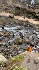 Crowds explore a muddy waterfall trail in Sidomulyo, Indonesia