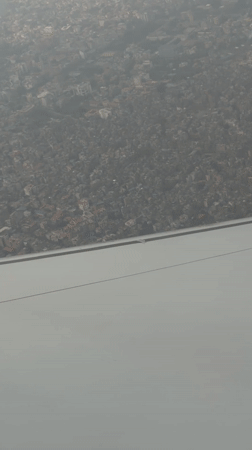 Aircraft passenger films hazy aerial view of Kathmandu cityscape