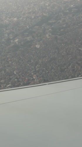Aircraft passenger films hazy aerial view of Kathmandu cityscape