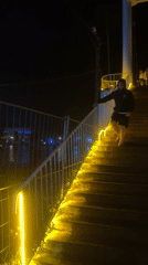 Yellow string lights glow along a nighttime staircase in Poti