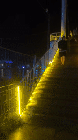 Yellow string lights glow along a nighttime staircase in Poti