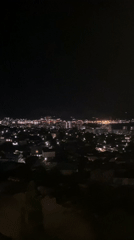 Nighttime aerial view captures illuminated Novorossiysk cityscape and waterfront